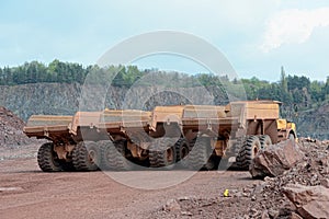 Three dumper trucks in a row in a quarry mine.