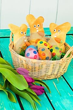 Three easter bunnies with colored easter eggs on a wooden tabel