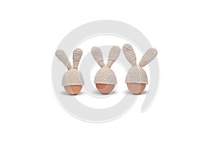 Three Easter eggs in crochet hats with bunny ears isolated on white