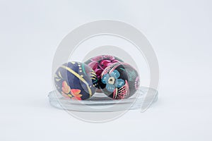 Three Easter eggs lie on a transparent plate on a white background