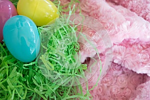 Three Easter eggs - yellow-pink-blue- on green grass and pink background