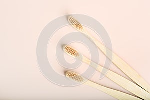 Three eco friendly natural bamboo toothbrushes on pink background.