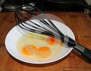 Three eggs in a bowl with a whisk
