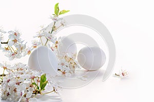 Three eggs and a branch of wild flowers on a white background as Easter arrangement, holiday greeting card, copy space, selected