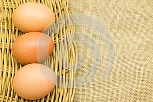 Three eggs in wicker basket on gunny sack background