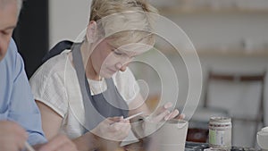 Three elderly people work on a potter's wheel in slow motion