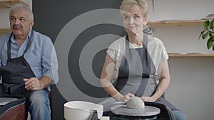 Three elderly people work on a potter's wheel in slow motion