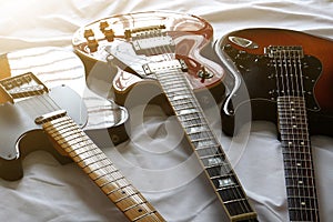 Three electric guitars placed on a white cloth, macro abstract