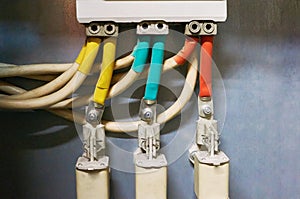 Three electrical high-voltage fuses connected to the colored wires. Industrial background.