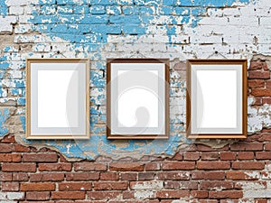 Three empty frames hanging on a distressed brick wall