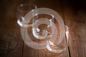 Three empty glasses on a brown wooden desk