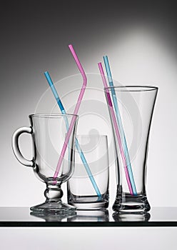 Three empty glasses with colored tubes for cocktail.