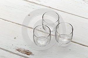 Three empty glasses on a white wooden table