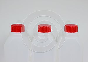 Three empty jerrycans of white plastic with red lids