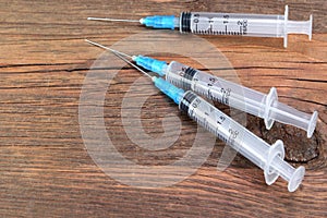 Three Empty Medical Syringes On Rough Wood Board