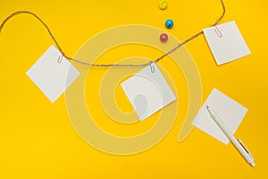 Three empty note papers attached to a rope on a yellow background