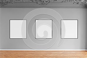 Three empty picture frames hanging on grey wall in gallery