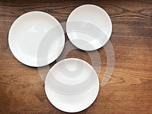 Three empty white plates on wooden table top view. Copy space
