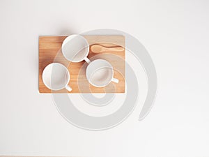 Three empty white teacups and a small wooden spoon