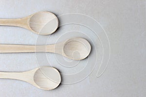 Three empty wooden spoons in the left side of the photo. Close up top view photo. With copy space. Eco kitchenware