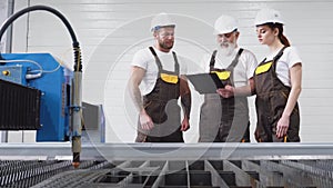 Three engineers inspecting plasma cutter.