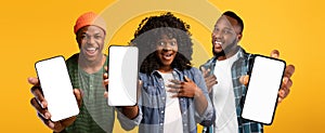 Three excited black people showing smartphones with white blank screen, mockup