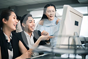 Three excited employees reading good news on line in a computer desktop at office