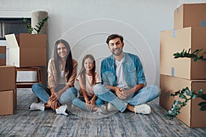 Young parents and their daughter posing happily in new house photo