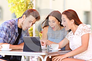 Three excited friends watching tablet content