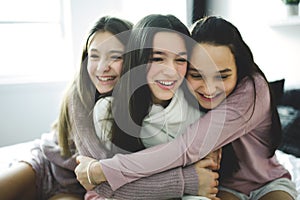 Three excited teenager girls having fun together, enjoying laze leisure time at home