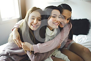 Three excited teenager girls having fun together, enjoying laze leisure time at home