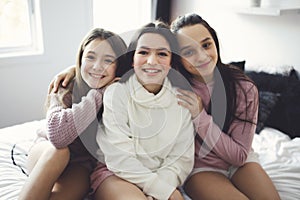 Three excited teenager girls having fun together, enjoying laze leisure time at home