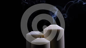 Three extinguished candles with smoke on a black background