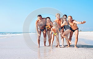 Three family generations on the one long shoot posing for group photo on the beach. Kids, teenagers, Parents and Grandparents