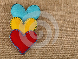 Three felt craft hearts, yellow, red and blue