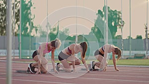 Three female athletes simultaneously start running marathon, rivalry, slow-motion. women standing on a starting line