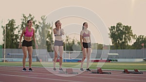 Three female athletes simultaneously start running marathon, rivalry, slow-motion. women standing on a starting line