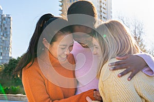 Three female friends affectionately hug each other having fun together laughing happy smiling.