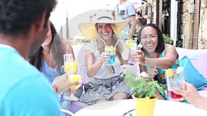 Three female friends drinking cocktails on terrace cafe in summer