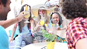 Three female friends drinking cocktails on terrace cafe in summer