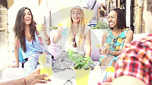 Three female friends drinking cocktails on terrace cafe in summer