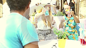 Three female friends drinking cocktails on terrace cafe in summer