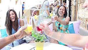 Three female friends drinking cocktails on terrace cafe in summer