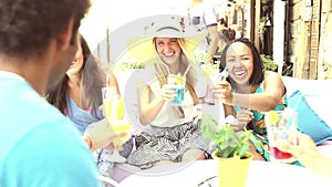 Three female friends drinking cocktails on terrace cafe in summer