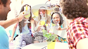 Three female friends drinking cocktails on terrace cafe in summer