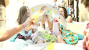 Three female friends drinking cocktails on terrace cafe in summer