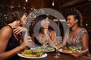 Three female friends eating dinner together at a restaurant