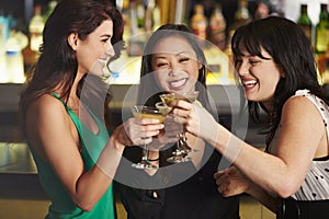 Three Female Friends Enjoying Drink In Cocktail Bar