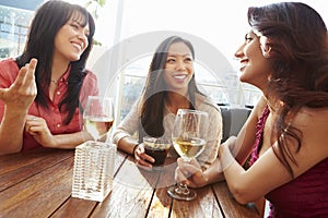 Three Female Friends Enjoying Drink At Outdoor Rooftop Bar