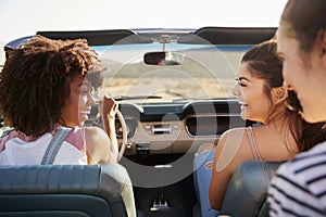 Three Female Friends Enjoying Road Trip In Open Top Classic Car